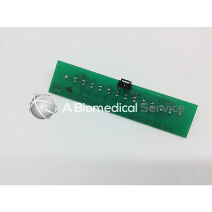 Green rectangular circuit board with silver soldered components and black connector for marquette dash alarm light assembly