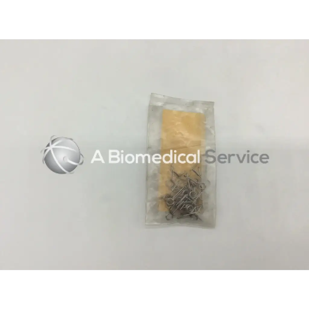 A clear plastic bag containing multiple metallic howmedica orthopedic fixation stop clips with a yellow paper insert