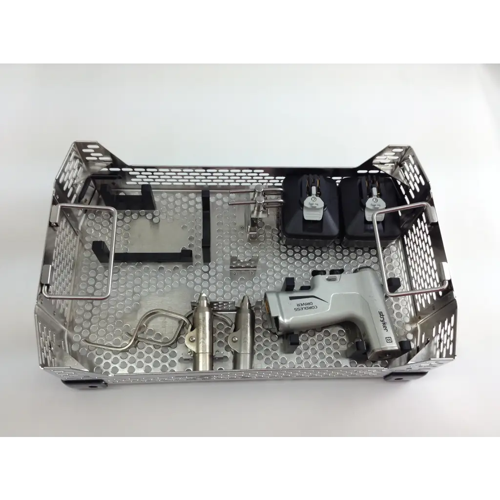 Silver metallic surgical instrument tray with perforated design holding dental tools in aesculap case for cordless driver set