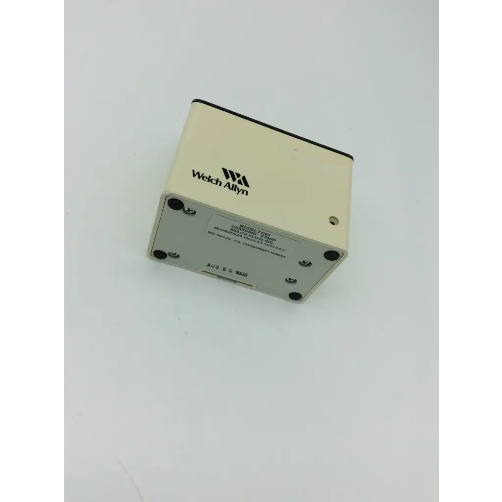 Cream-colored welch allyn model 7235 diagnostic device with black-trimmed top on silver metal welch allyn charging stand 71123