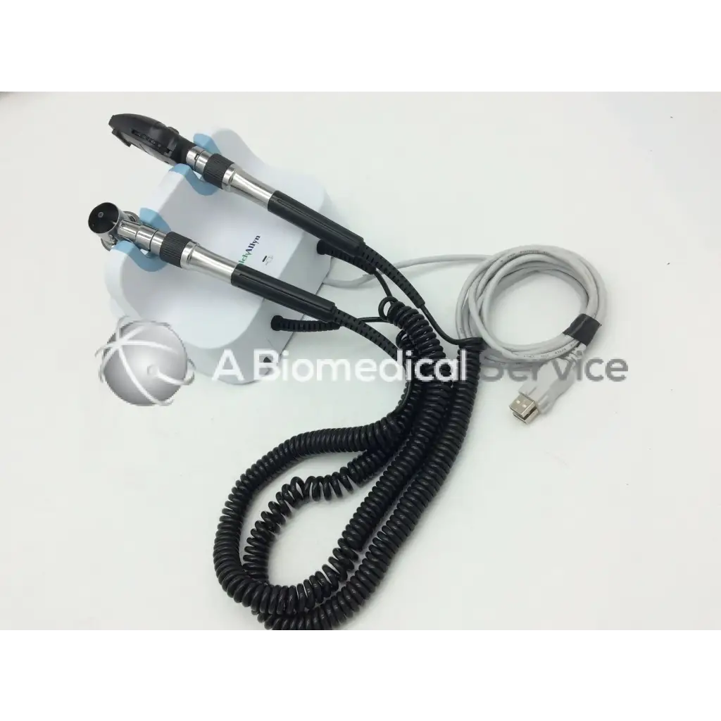 Welch allyn green series dual-ended black and silver endoscope with coiled cables on white wall transformer opthalmoscope base