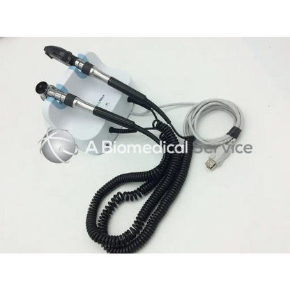 Welch allyn green series dual-ended black and silver endoscope with coiled cables on white wall transformer opthalmoscope base